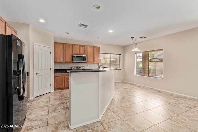 kitchen with pendant lighting, appliances with stainless steel finishes, a center island with sink, and light tile patterned flooring