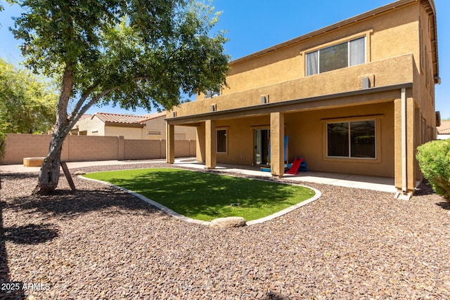 back of property with a yard and a patio