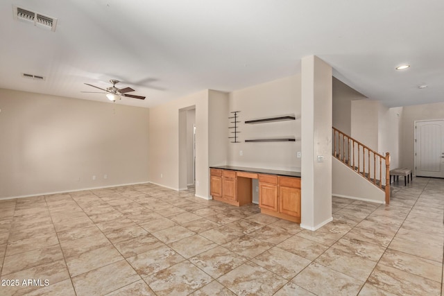 unfurnished living room featuring ceiling fan and built in desk