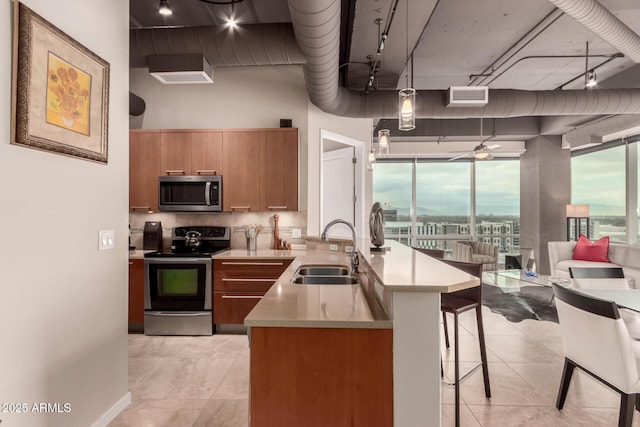 kitchen with sink, hanging light fixtures, appliances with stainless steel finishes, a kitchen breakfast bar, and backsplash