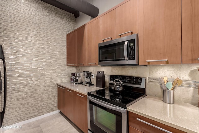 kitchen featuring decorative backsplash, light tile patterned flooring, light stone countertops, and appliances with stainless steel finishes