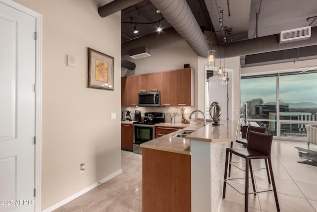 kitchen featuring sink, a breakfast bar area, decorative backsplash, kitchen peninsula, and stainless steel appliances