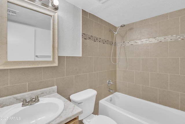 bathroom featuring visible vents, toilet, shower / bathtub combination, vanity, and tile walls