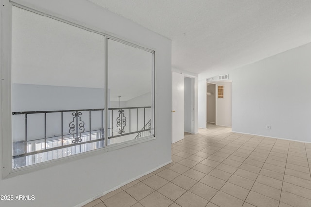 spare room with light tile patterned floors, visible vents, and a textured ceiling