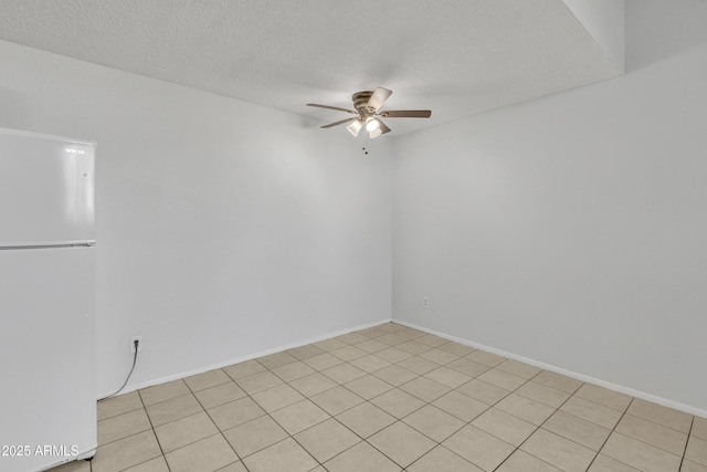 spare room with ceiling fan, a textured ceiling, and baseboards