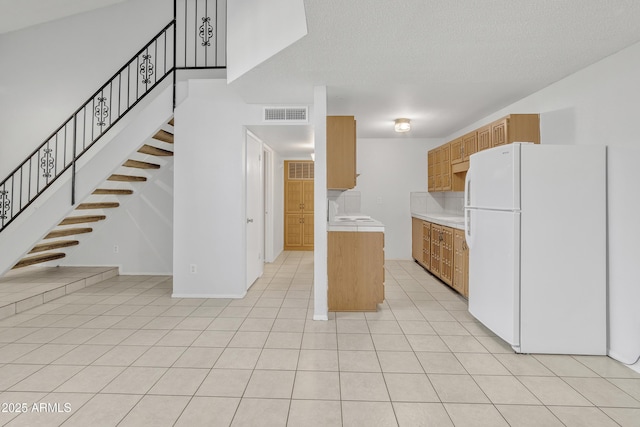 kitchen with light tile patterned floors, visible vents, a towering ceiling, light countertops, and freestanding refrigerator