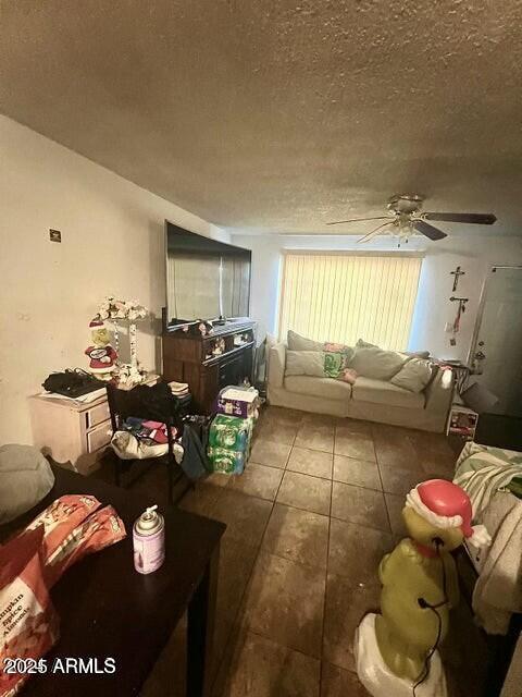 living room with ceiling fan, tile patterned floors, and a textured ceiling