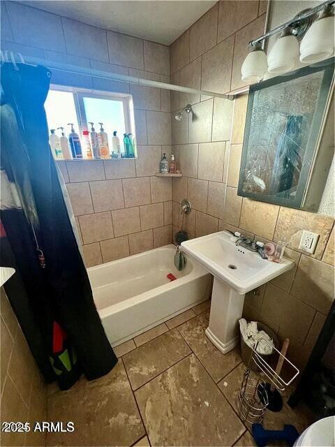 bathroom with shower / bath combination with curtain, tile walls, and backsplash