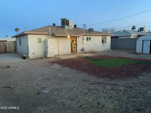 rear view of house featuring cooling unit, a storage unit, and a patio