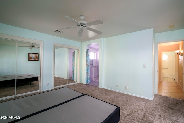 unfurnished bedroom featuring multiple closets, carpet floors, and ceiling fan