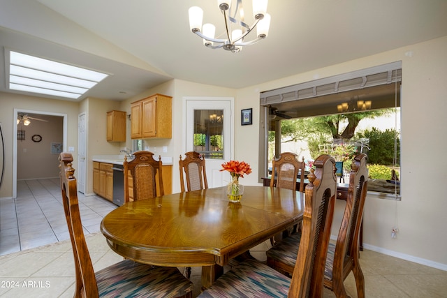 tiled dining room with lofted ceiling, a healthy amount of sunlight, and ceiling fan with notable chandelier