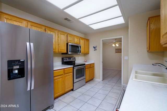 kitchen with appliances with stainless steel finishes, sink, light tile patterned floors, and ceiling fan