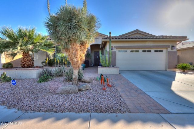 view of front of home with a garage, a tile roof, driveway, and stucco siding