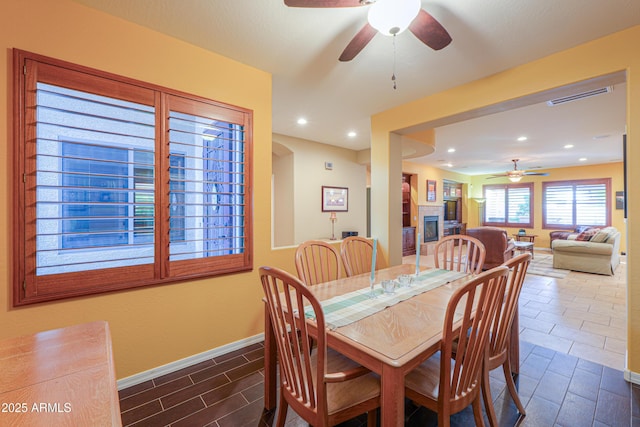 dining room featuring baseboards, visible vents, a glass covered fireplace, recessed lighting, and a ceiling fan