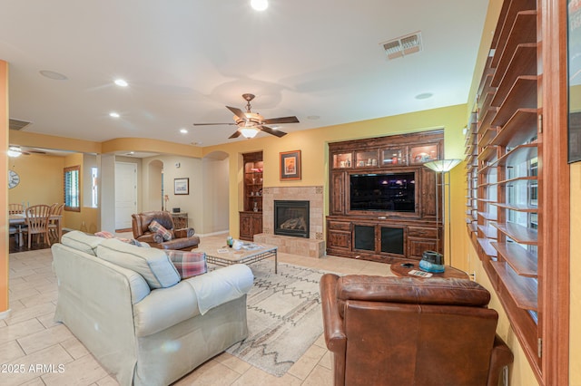 living area with ceiling fan, arched walkways, visible vents, and light tile patterned floors