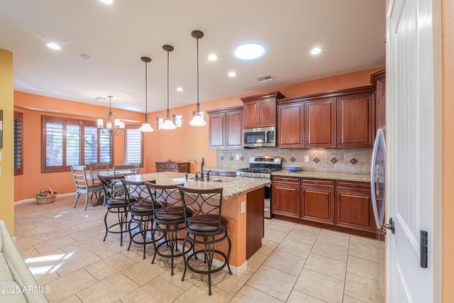 kitchen with backsplash, visible vents, a sink, a kitchen bar, and appliances with stainless steel finishes