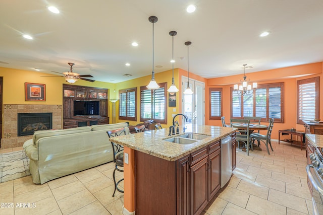 kitchen with a sink, pendant lighting, light stone countertops, a tile fireplace, and appliances with stainless steel finishes