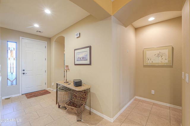 entrance foyer featuring arched walkways, baseboards, visible vents, recessed lighting, and light tile patterned floors