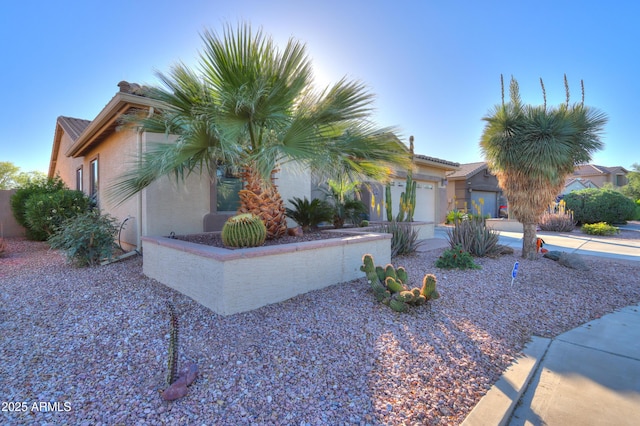 view of front of property featuring a tile roof, an attached garage, concrete driveway, and stucco siding