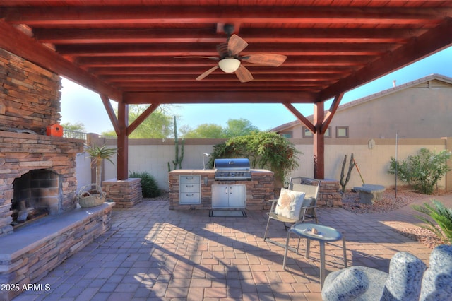 view of patio with a fenced backyard, an outdoor kitchen, an outdoor stone fireplace, and area for grilling