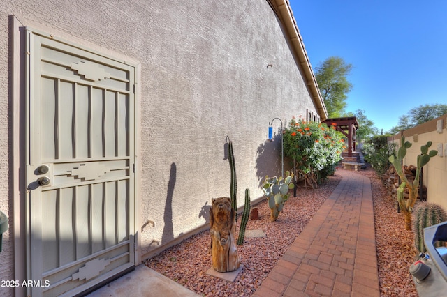 view of side of property with fence and stucco siding