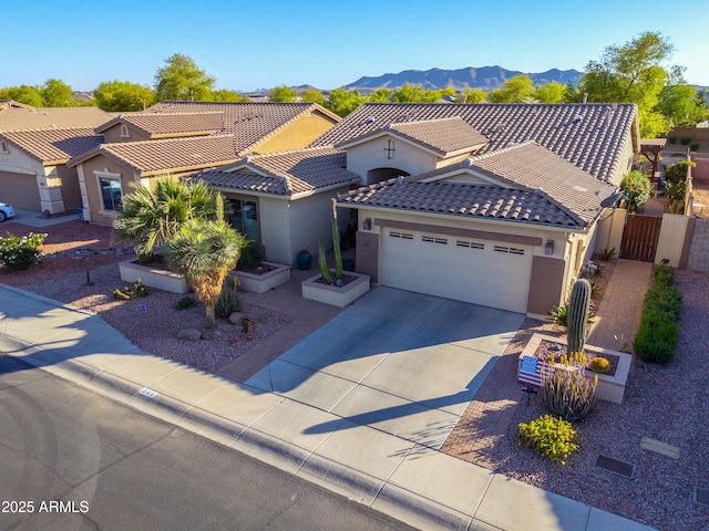 mediterranean / spanish home featuring a tile roof, driveway, a mountain view, a garage, and stucco siding