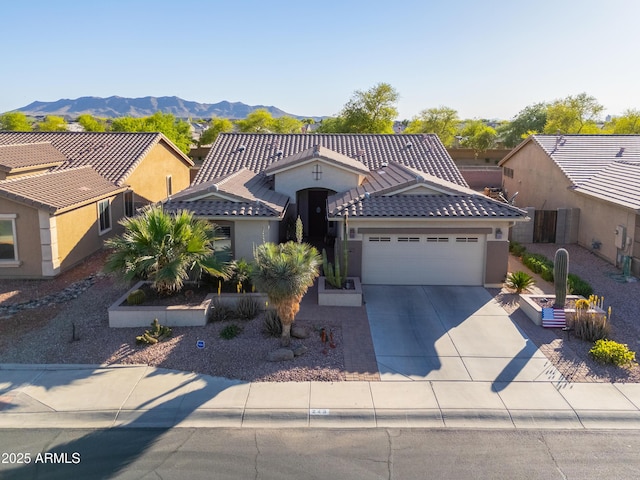 view of front of house featuring a tile roof, a mountain view, concrete driveway, an attached garage, and stucco siding