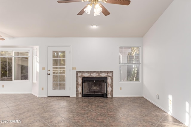 unfurnished living room featuring vaulted ceiling, ceiling fan, a tiled fireplace, and tile patterned flooring