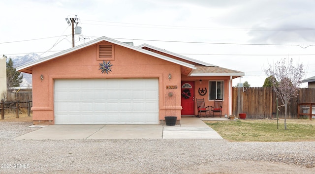 ranch-style home with stucco siding, an attached garage, gravel driveway, and fence