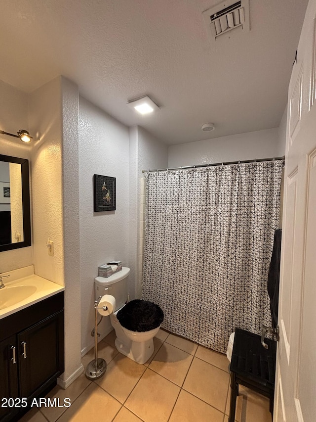 bathroom with tile patterned flooring, visible vents, toilet, vanity, and a textured ceiling