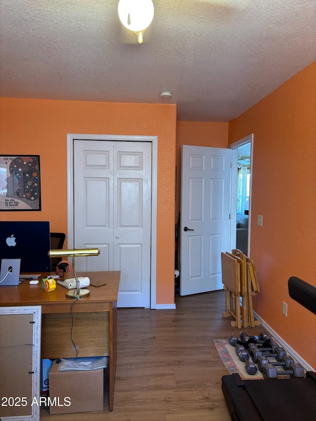 home office featuring a textured ceiling, baseboards, and wood finished floors