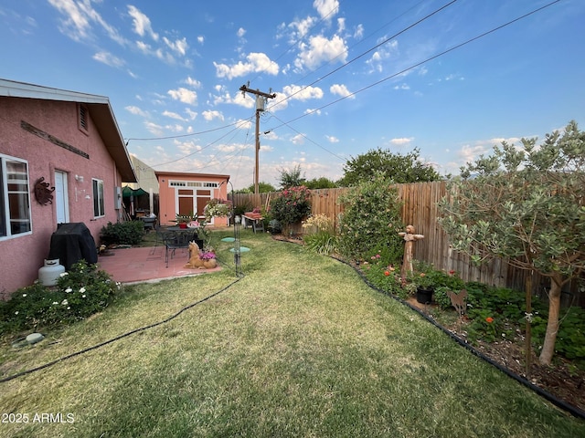 view of yard with an outbuilding, a fenced backyard, a storage shed, and a patio area