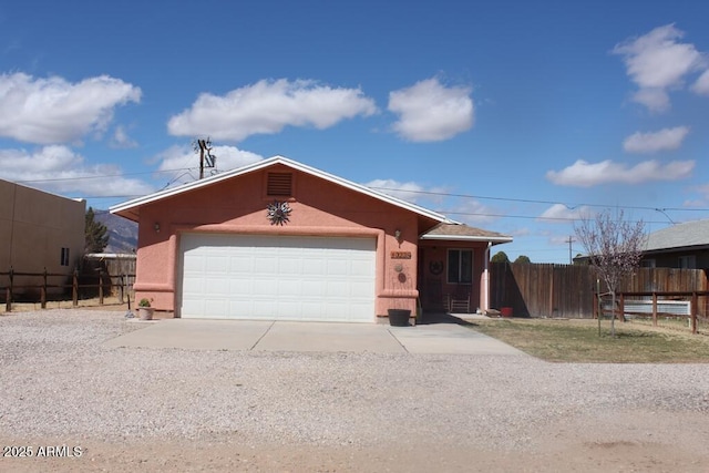 view of front facade with concrete driveway, an attached garage, and fence