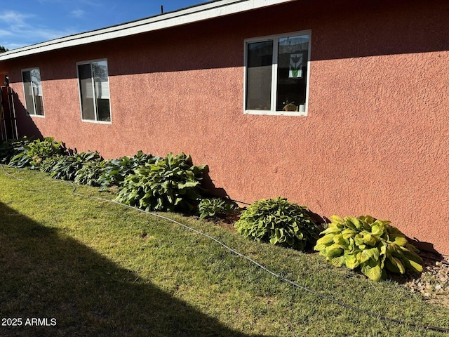 view of side of home with stucco siding and a yard