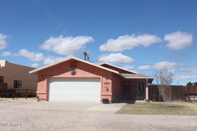 view of front of house featuring stucco siding, an attached garage, concrete driveway, and fence