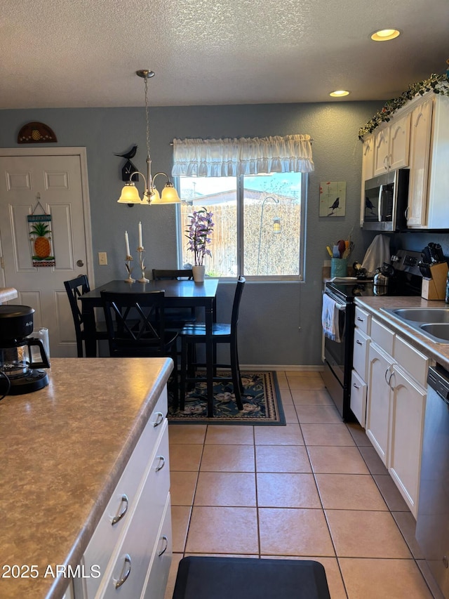 kitchen featuring a notable chandelier, black electric range, stainless steel microwave, light tile patterned flooring, and dishwashing machine