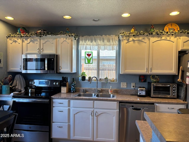 kitchen featuring a toaster, appliances with stainless steel finishes, white cabinetry, and a sink