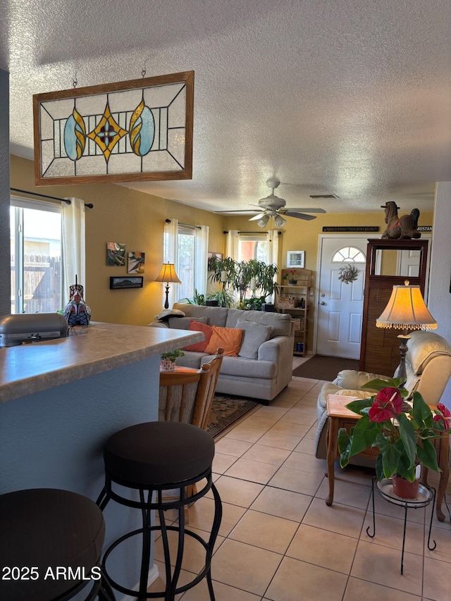 living area featuring light tile patterned floors, a textured ceiling, and a ceiling fan