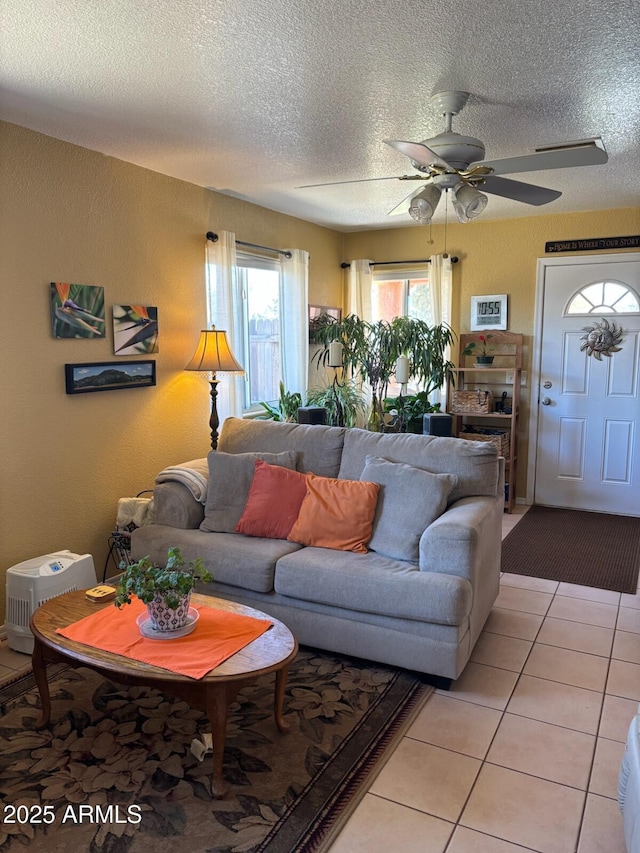 living area featuring light tile patterned floors, a textured ceiling, and a ceiling fan