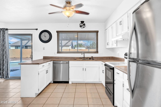 kitchen featuring sink, white cabinets, light tile patterned floors, custom range hood, and appliances with stainless steel finishes