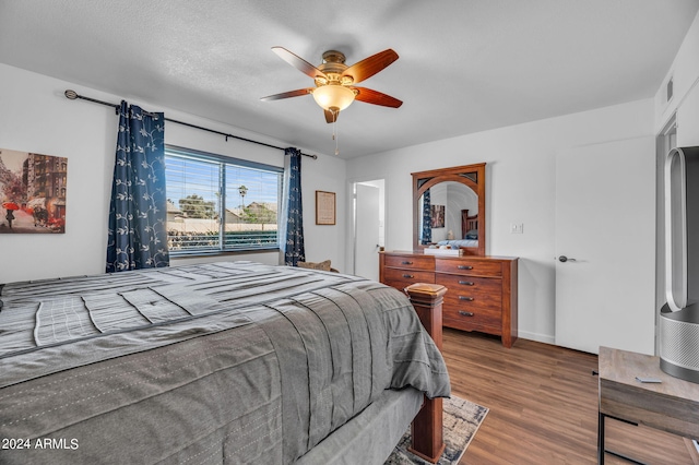 bedroom featuring hardwood / wood-style floors, ceiling fan, and a textured ceiling