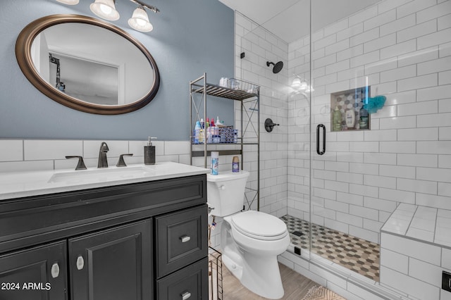 bathroom featuring vanity, toilet, wood-type flooring, and a shower with door