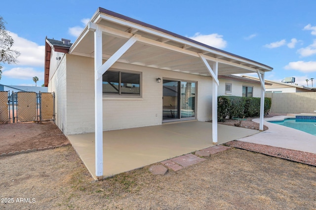 rear view of house with a fenced in pool and a patio area