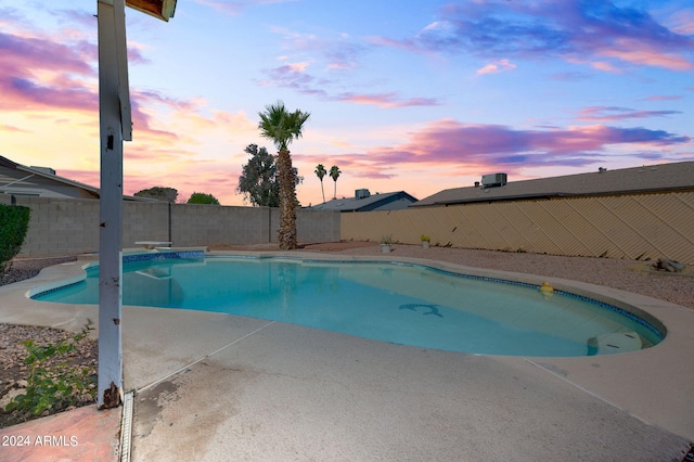 pool at dusk featuring a patio area