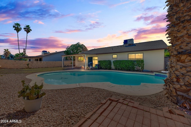 pool at dusk with a patio area and central air condition unit