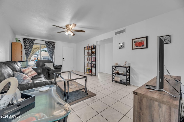 living room with ceiling fan, light tile patterned floors, and a textured ceiling