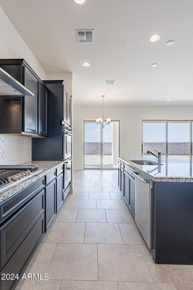 kitchen featuring backsplash, stainless steel appliances, sink, pendant lighting, and a chandelier