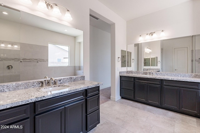 bathroom featuring tile patterned floors, vanity, and a tile shower