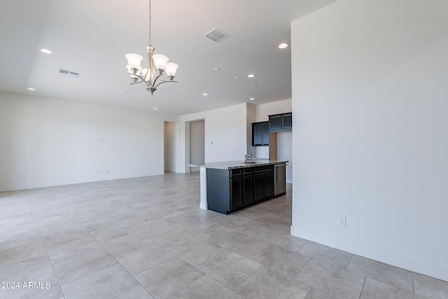 kitchen with pendant lighting, a center island with sink, sink, light stone countertops, and a chandelier