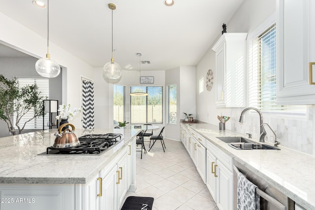 kitchen with white cabinetry, sink, decorative light fixtures, and light stone countertops